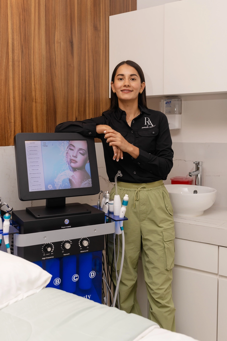 Redna Aesthetics team member standing next to treatment equipment in the clinic